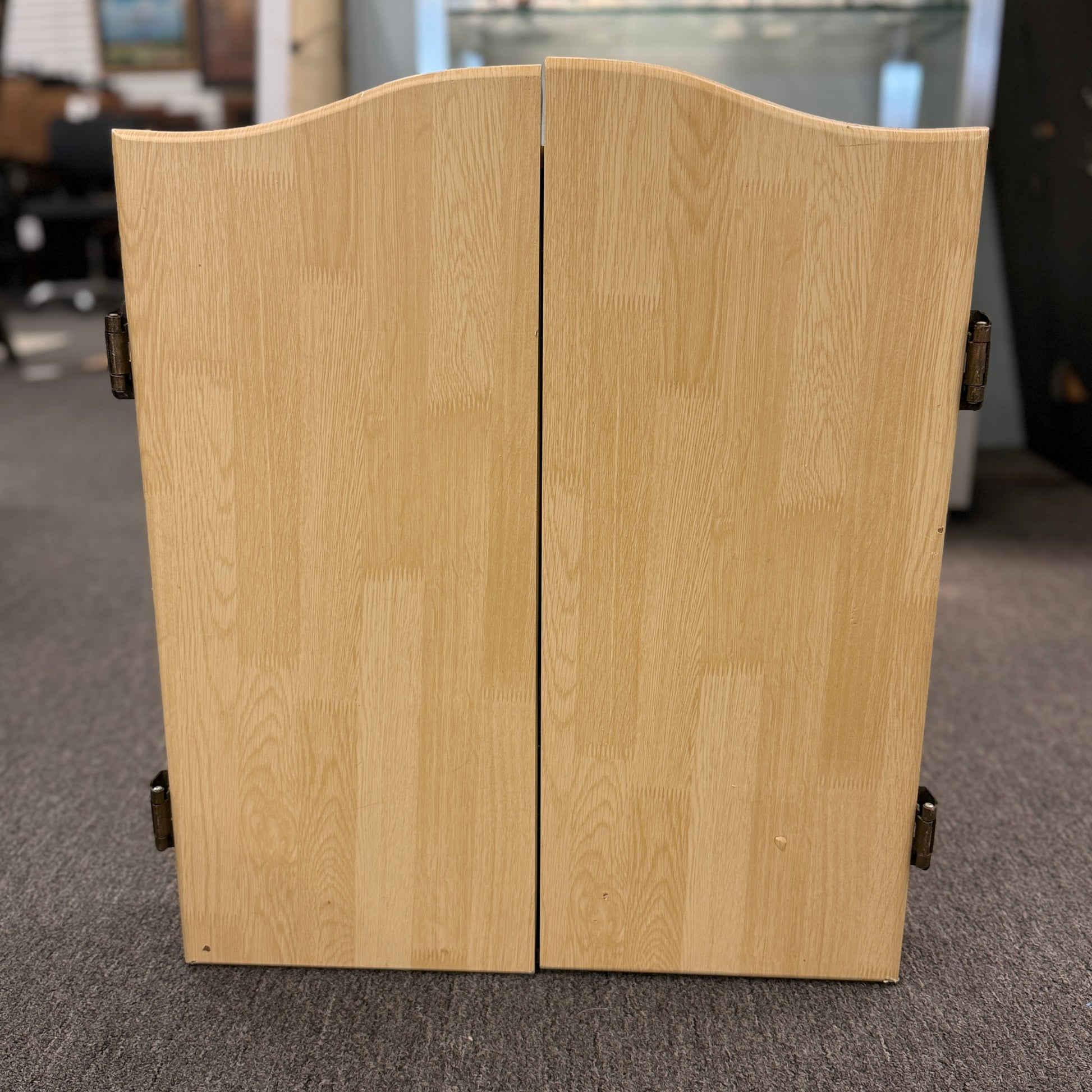 Wood dartboard cabinet opened to reveal a classic bristle dartboard with green Cricket scoreboards on the inside of both cabinet doors.