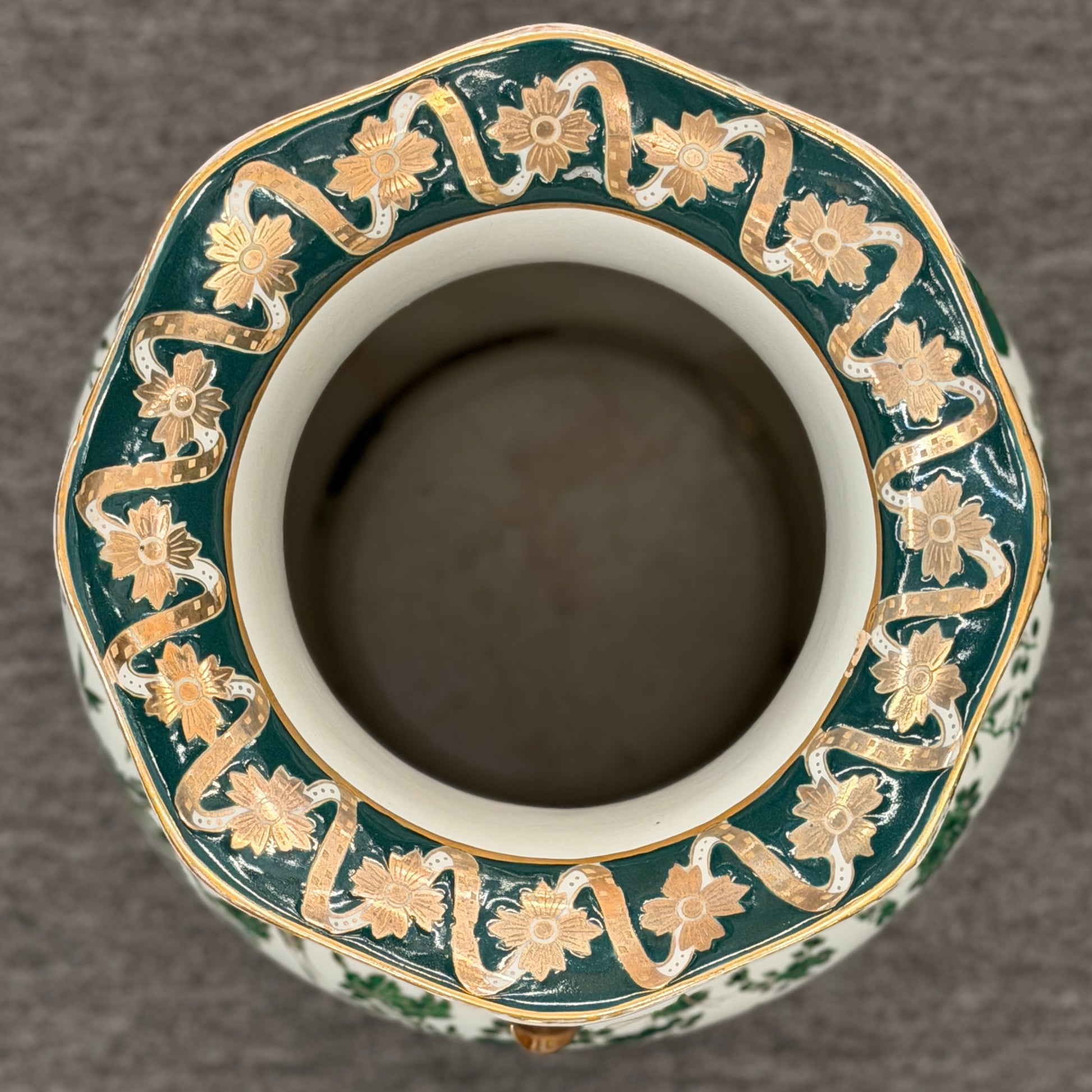 Tall ceramic vase with green and white floral patterns, sculpted gold-tone handles, a classical portrait medallion, and a matching pedestal saucer.