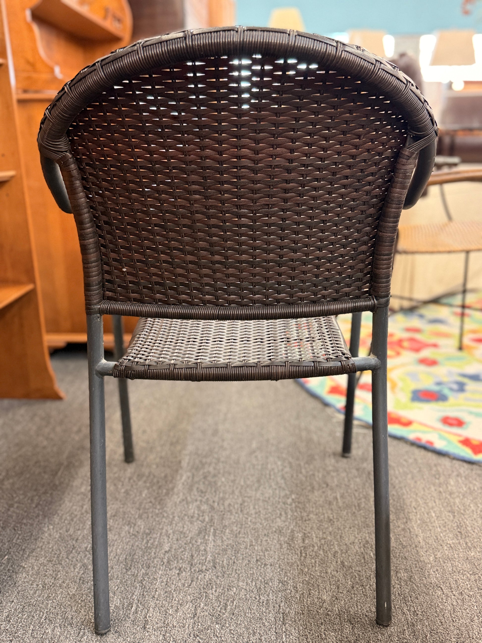 A 5-piece patio dining set featuring a square paneled top table with an umbrella hole and four dark woven resin wicker armchairs on iron frames.