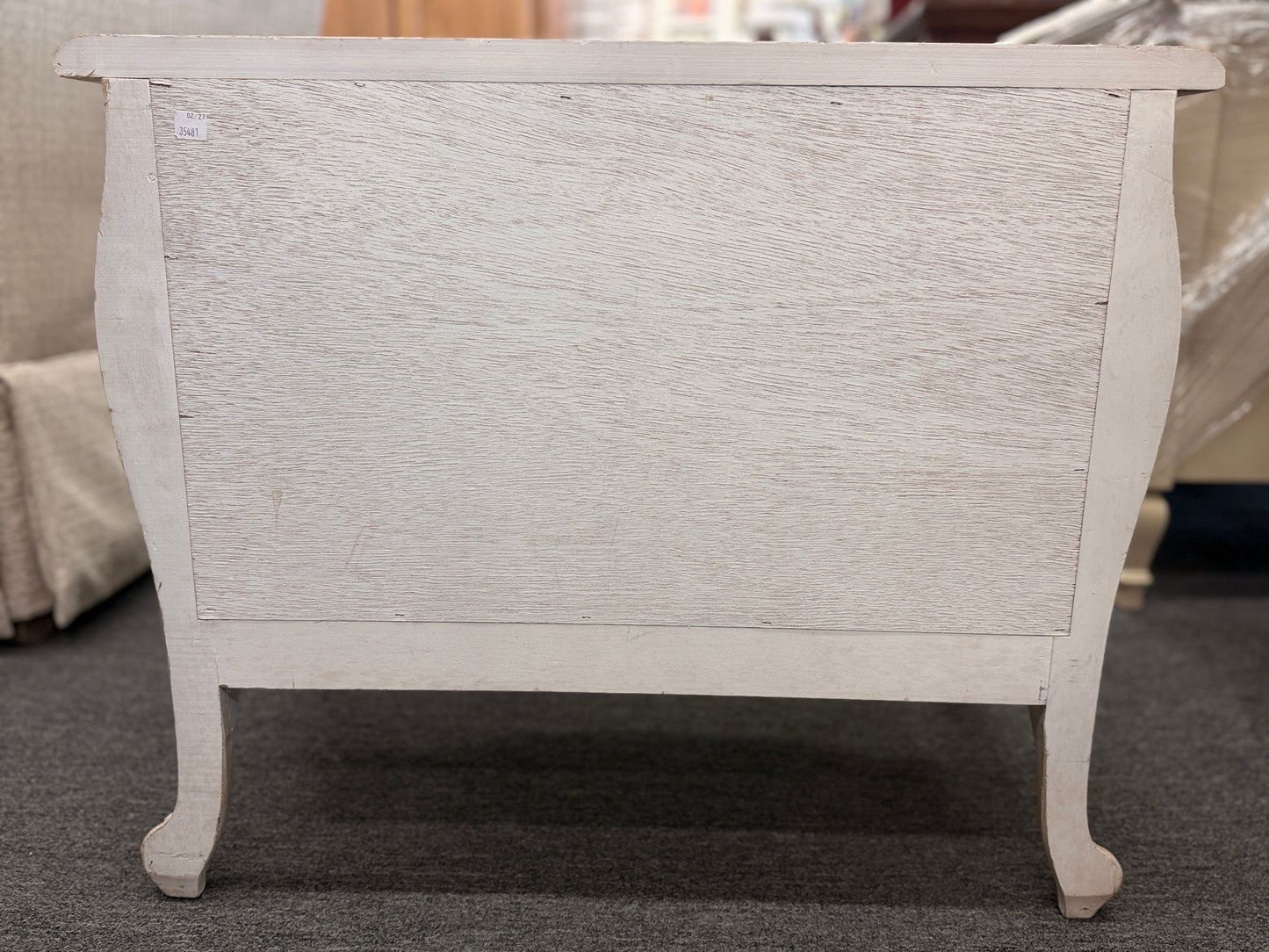 A French Provincial style two-drawer nightstand in a distressed antique-white finish featuring a serpentine front, cabriole legs, and ornate iron pulls.