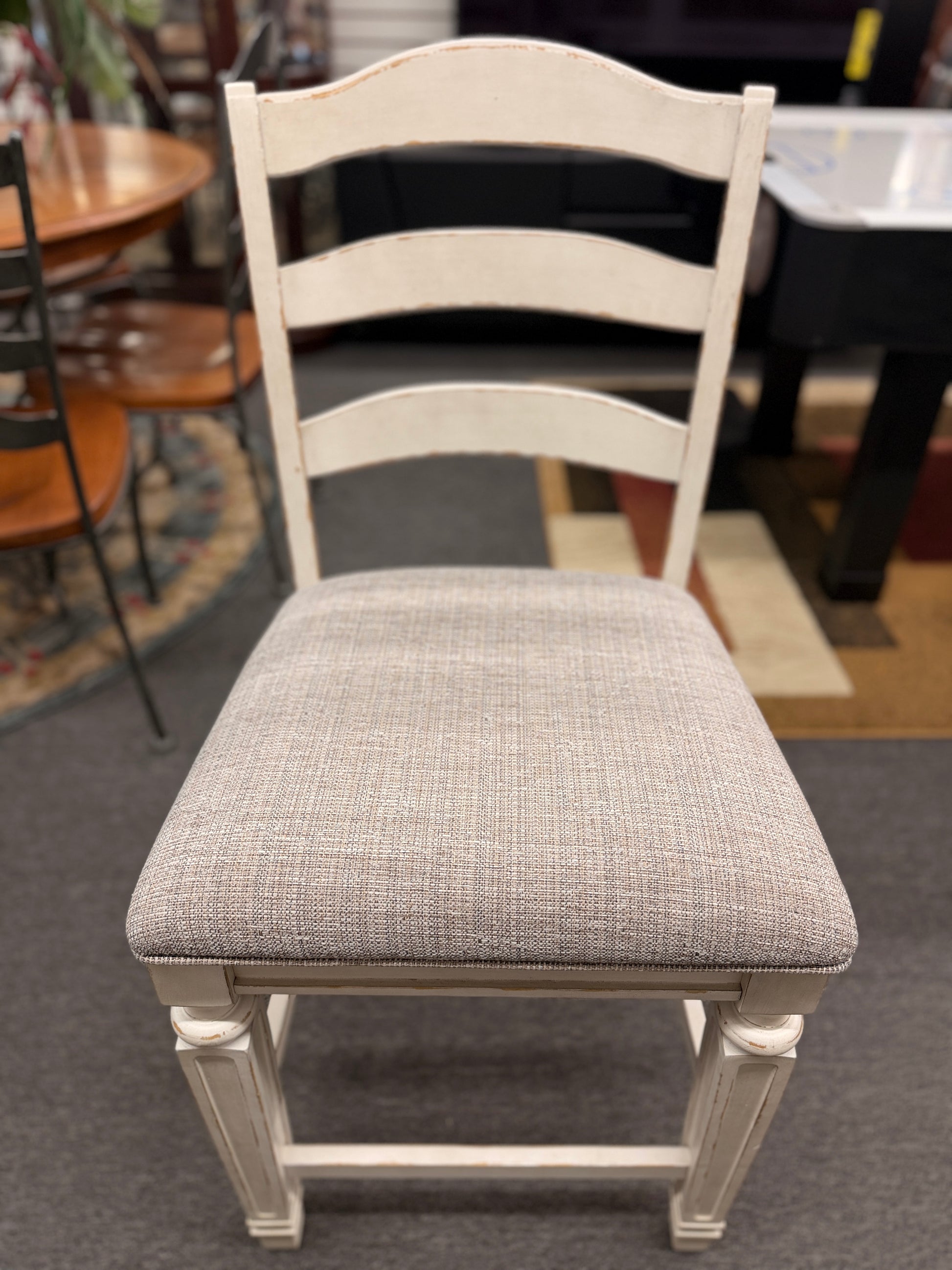 A two-tone counter-height dining set featuring a brown wood top rectangular table and six distressed white chairs with textured grey upholstered seats.