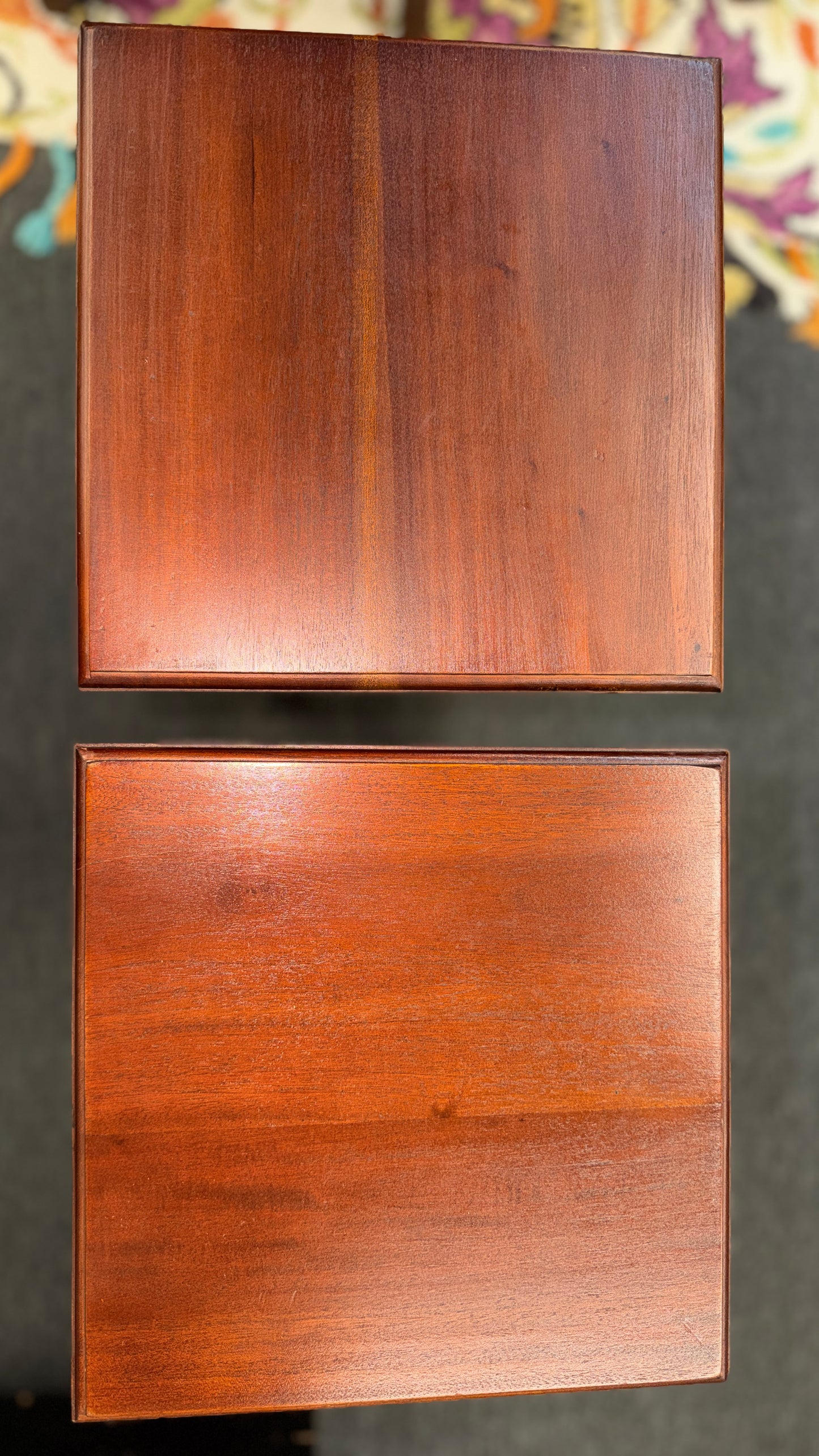 A pair of tall slim wooden side tables featuring square tops, lower display shelves, and cross-brace side details.