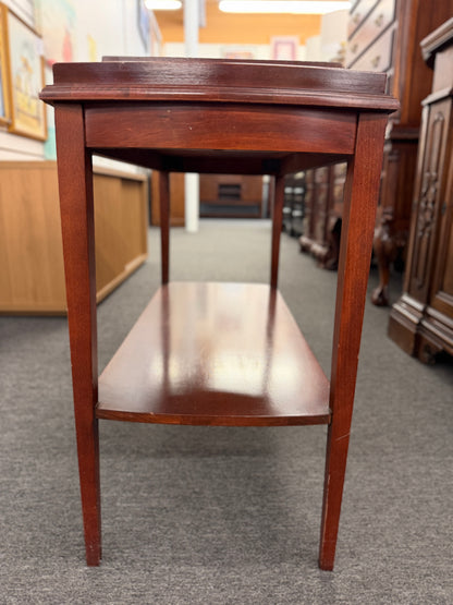A classic mahogany-finished wooden console entry table featuring a center drawer with oval brass pull, tapered legs, and a lower shelf.