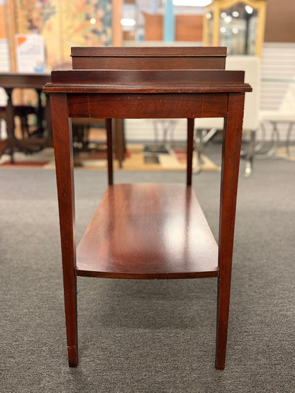 A classic mahogany-finished wooden console entry table featuring a center drawer with oval brass pull, tapered legs, and a lower shelf.
