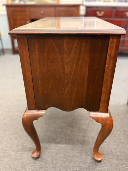 A traditional wooden lowboy accent dresser featuring four drawers with brass batwing drop pulls, a scalloped apron, and cabriole legs.