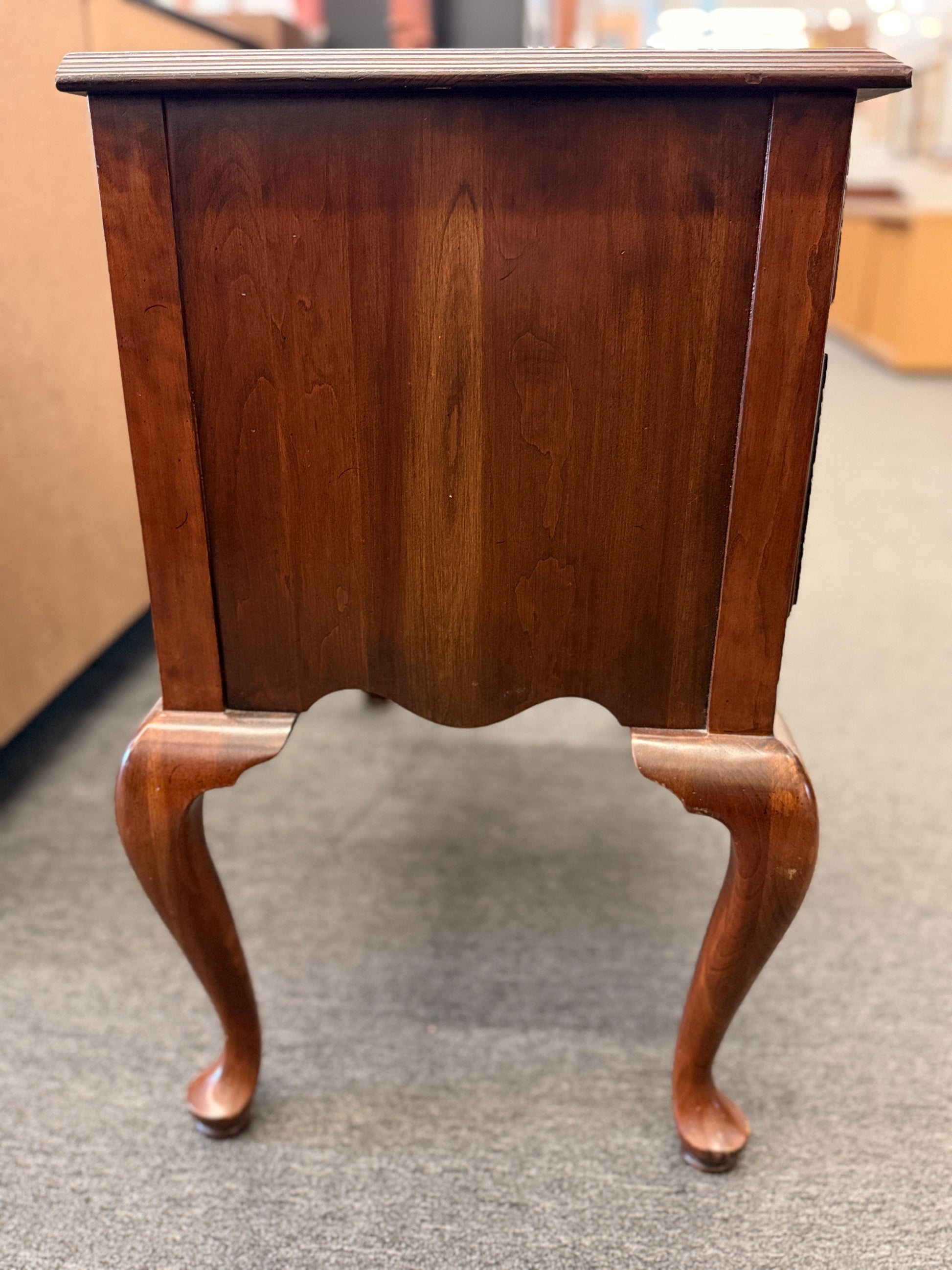 A traditional wooden lowboy accent dresser featuring four drawers with brass batwing drop pulls, a scalloped apron, and cabriole legs.