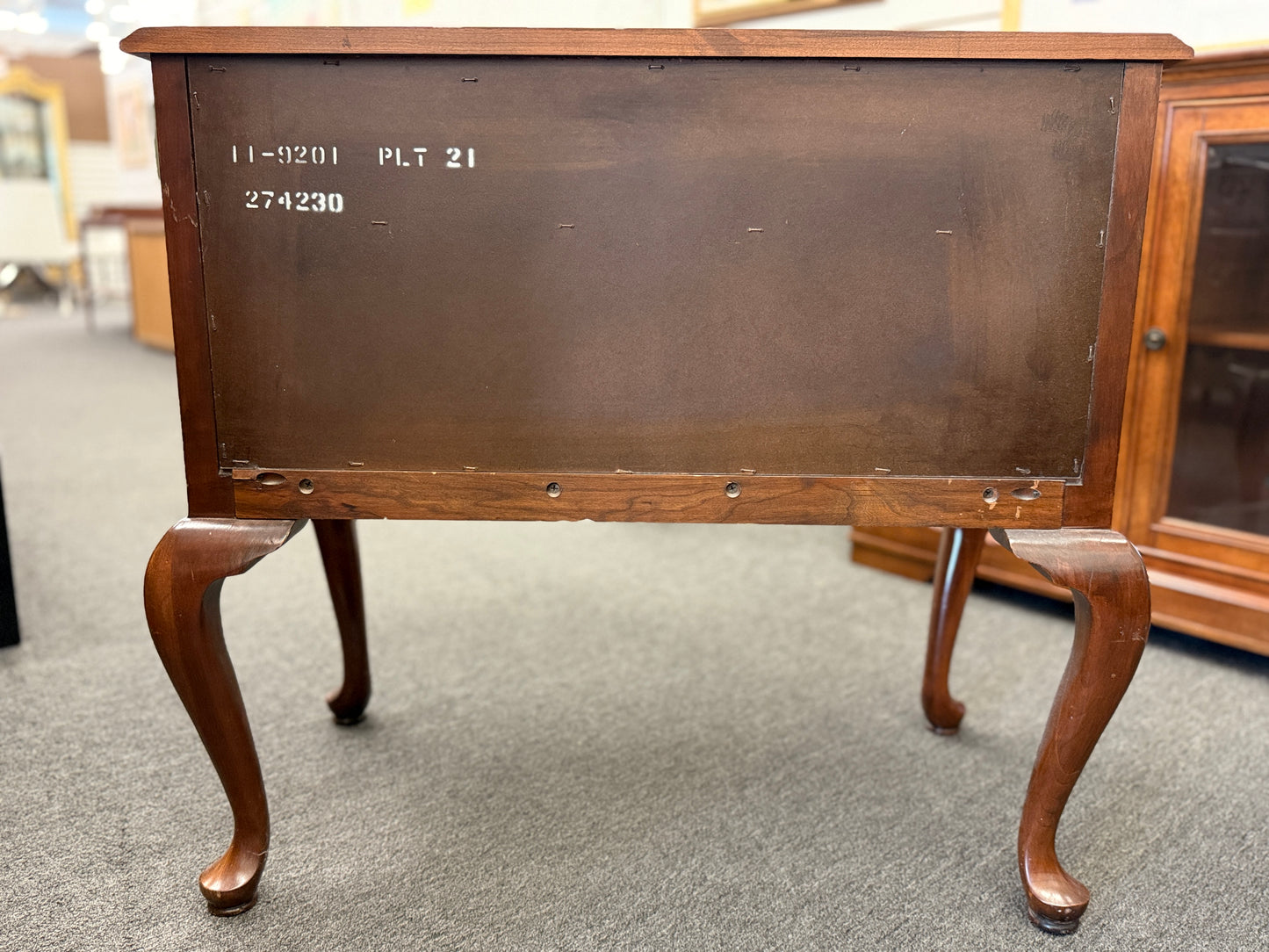 A traditional wooden lowboy accent dresser featuring four drawers with brass batwing drop pulls, a scalloped apron, and cabriole legs.