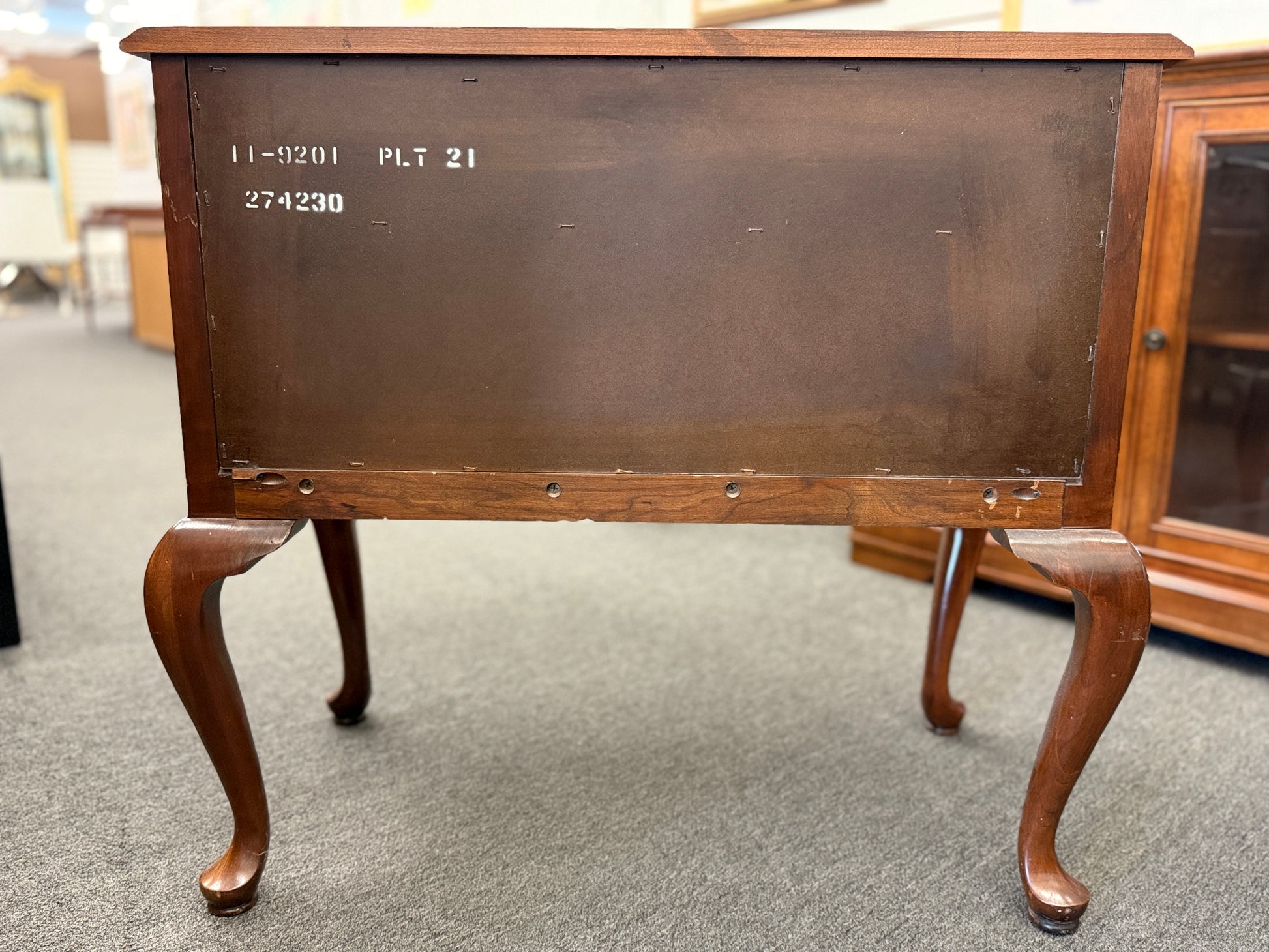 A traditional wooden lowboy accent dresser featuring four drawers with brass batwing drop pulls, a scalloped apron, and cabriole legs.