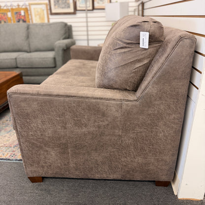 A plush two-seater sleeper sofa with pillow-top backrests and tapered track arms in textured distressed taupe-brown fabric.