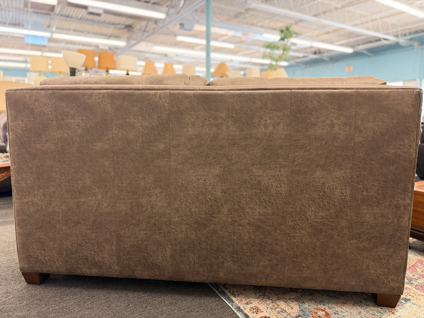 A plush two-seater sleeper sofa with pillow-top backrests and tapered track arms in textured distressed taupe-brown fabric.