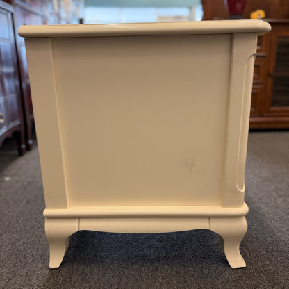 An off-white wooden nightstand featuring a single drawer with a turned knob, an open lower cubby, and curved cabriole legs.