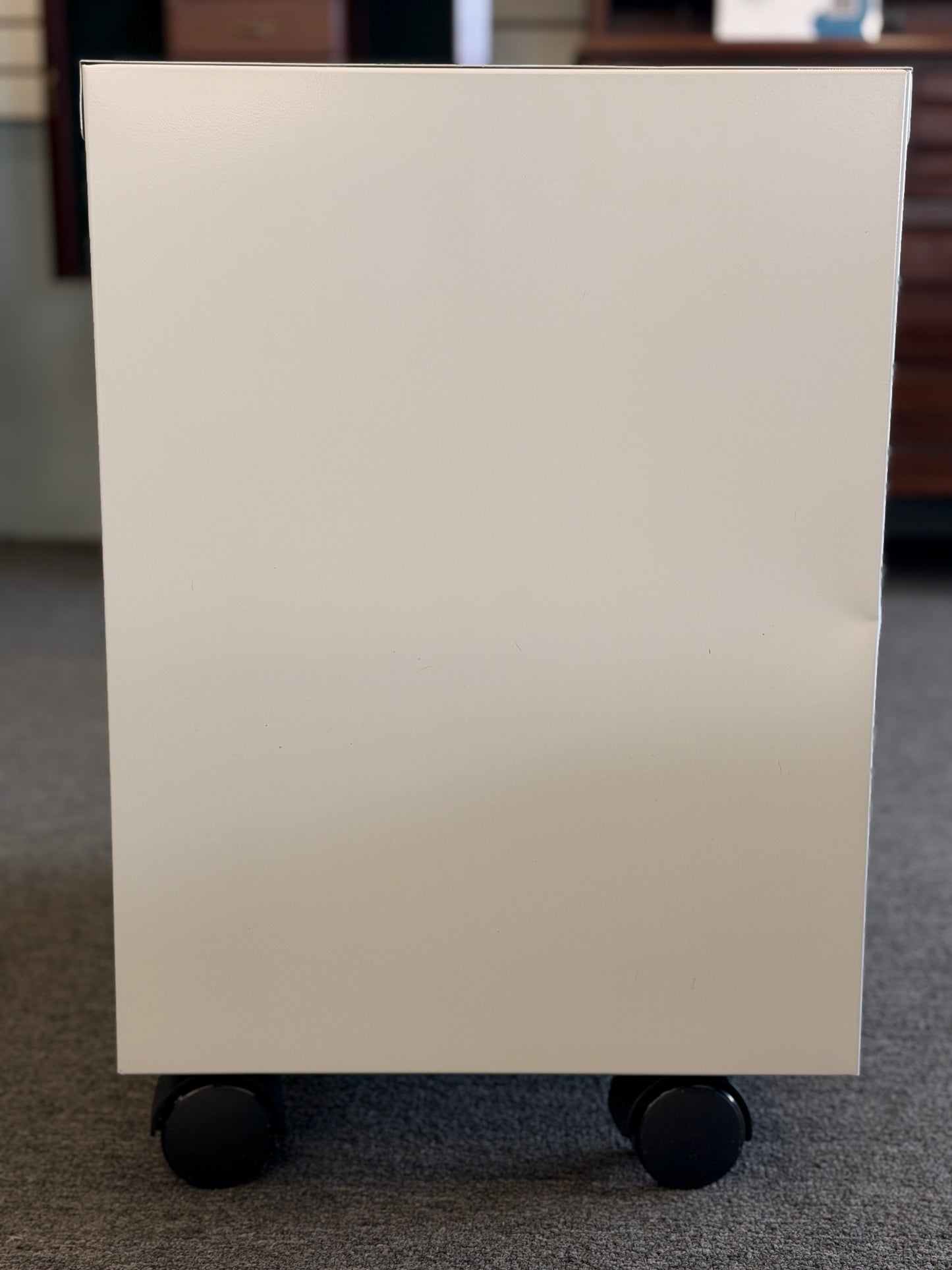 A minimalist two-drawer under-desk pedestal file cabinet featuring curved metal handles, a top lock, and dual casters in good condition.