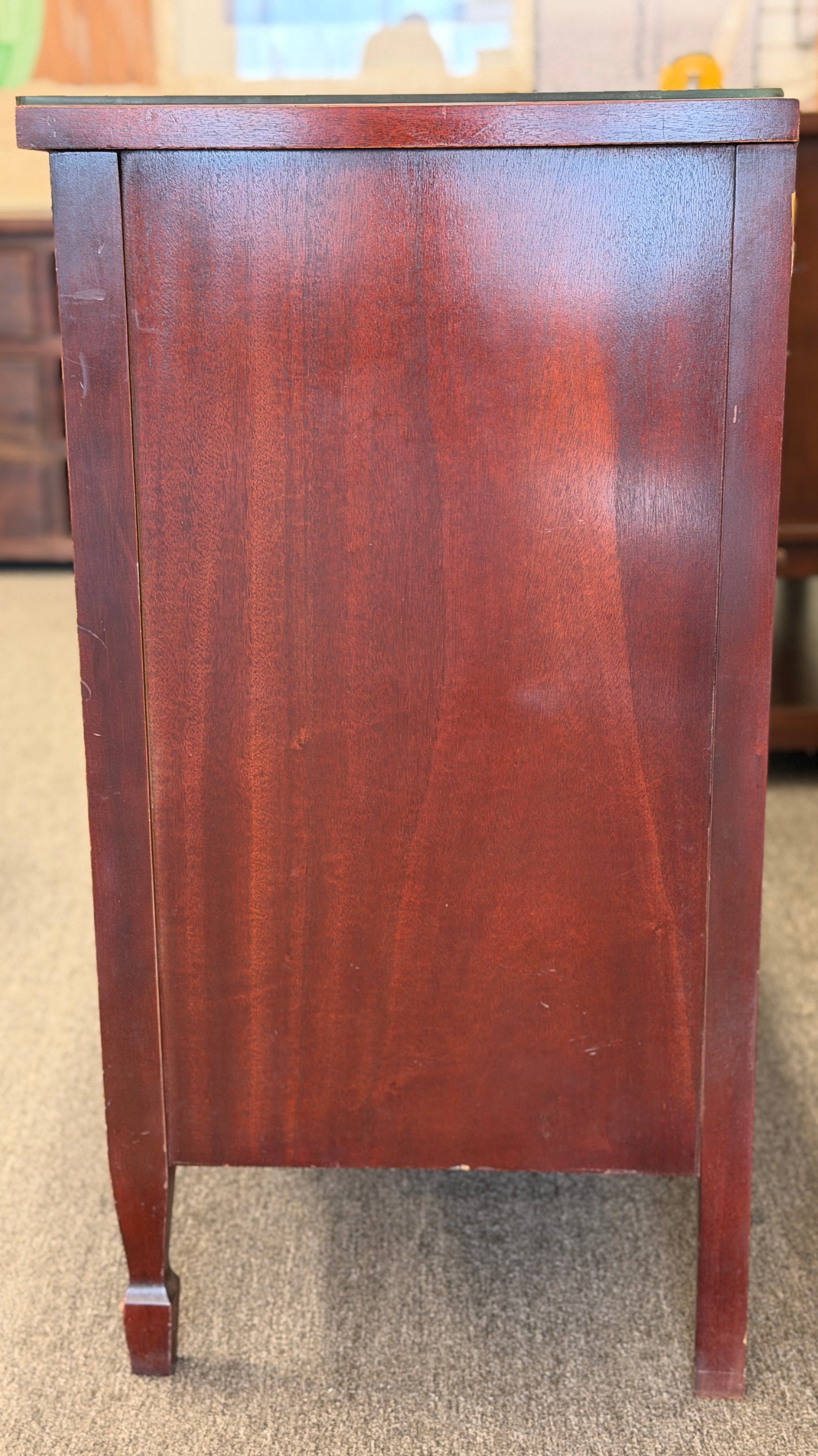 A vintage multi-drawer dresser in a rich reddish-brown wood finish with a serpentine front, brass handles, and a glass top in good condition.