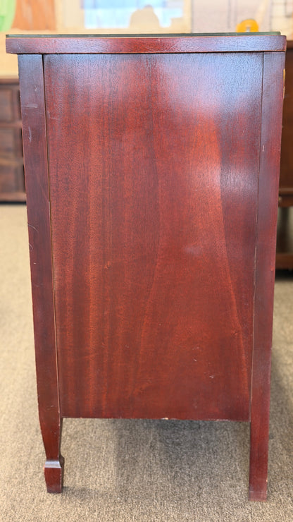 A vintage multi-drawer dresser in a rich reddish-brown wood finish with a serpentine front, brass handles, and a glass top in good condition.