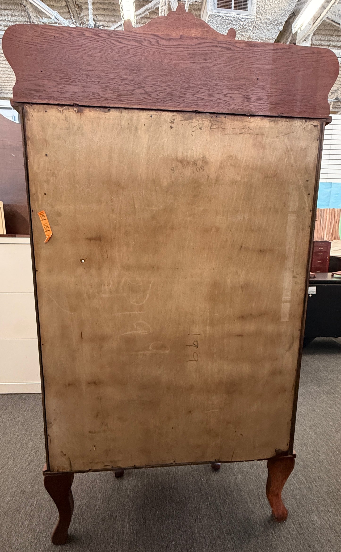 An antique-style oak curio cabinet featuring curved glass sides, an arched door with key hardware, interior shelves, and a carved pediment in good condition.