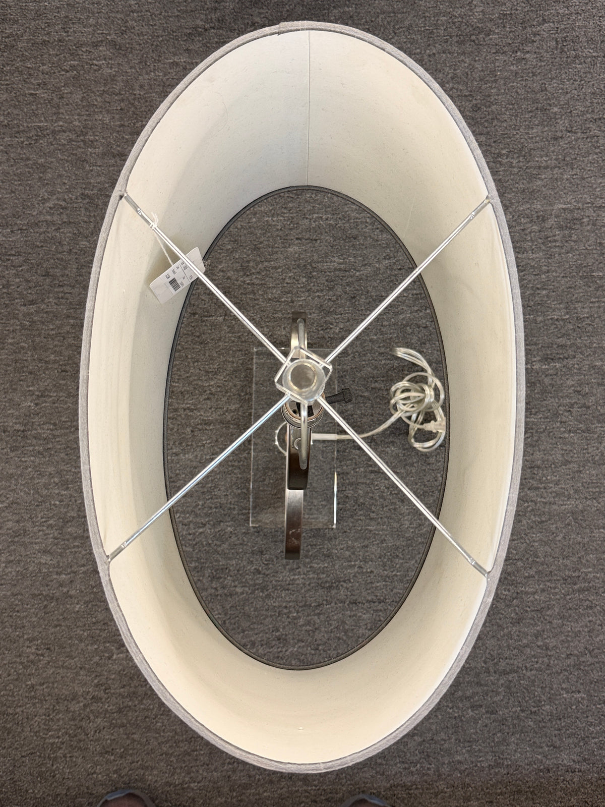 A contemporary table lamp featuring an intertwined dual-ring brushed nickel body, a clear acrylic base, and a textured gray drum shade in excellent condition.