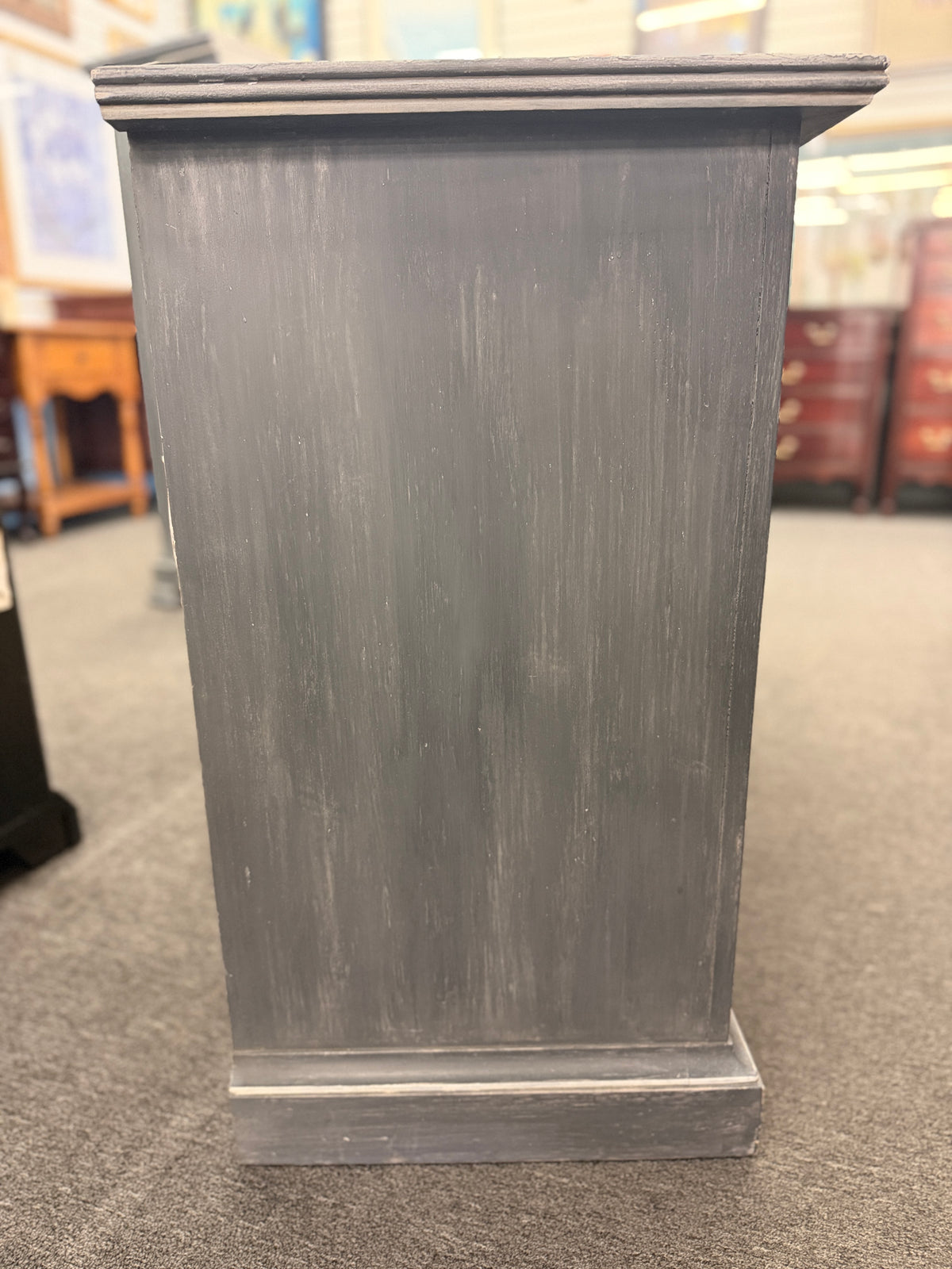 A six-drawer double dresser in a distressed charcoal black finish framed with light pinstripe bordering and ornate round brass-finish pull knobs in good condition.