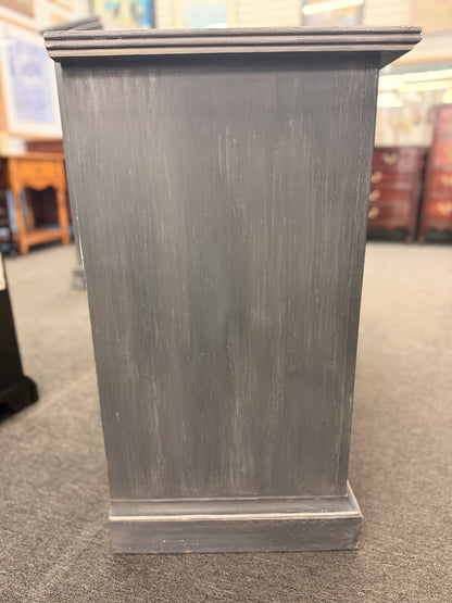 A six-drawer double dresser in a distressed charcoal black finish framed with light pinstripe bordering and ornate round brass-finish pull knobs in good condition.