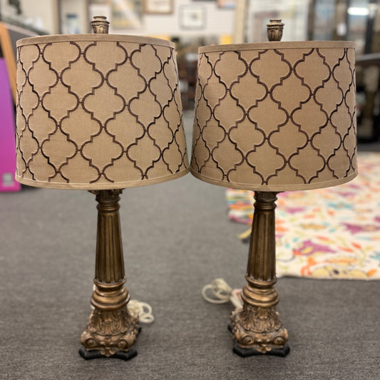 A matching pair of elegant table lamps with fluted column-style antique bronze bases and tan drum shades featuring a dark brown embroidered Moroccan trellis pattern.