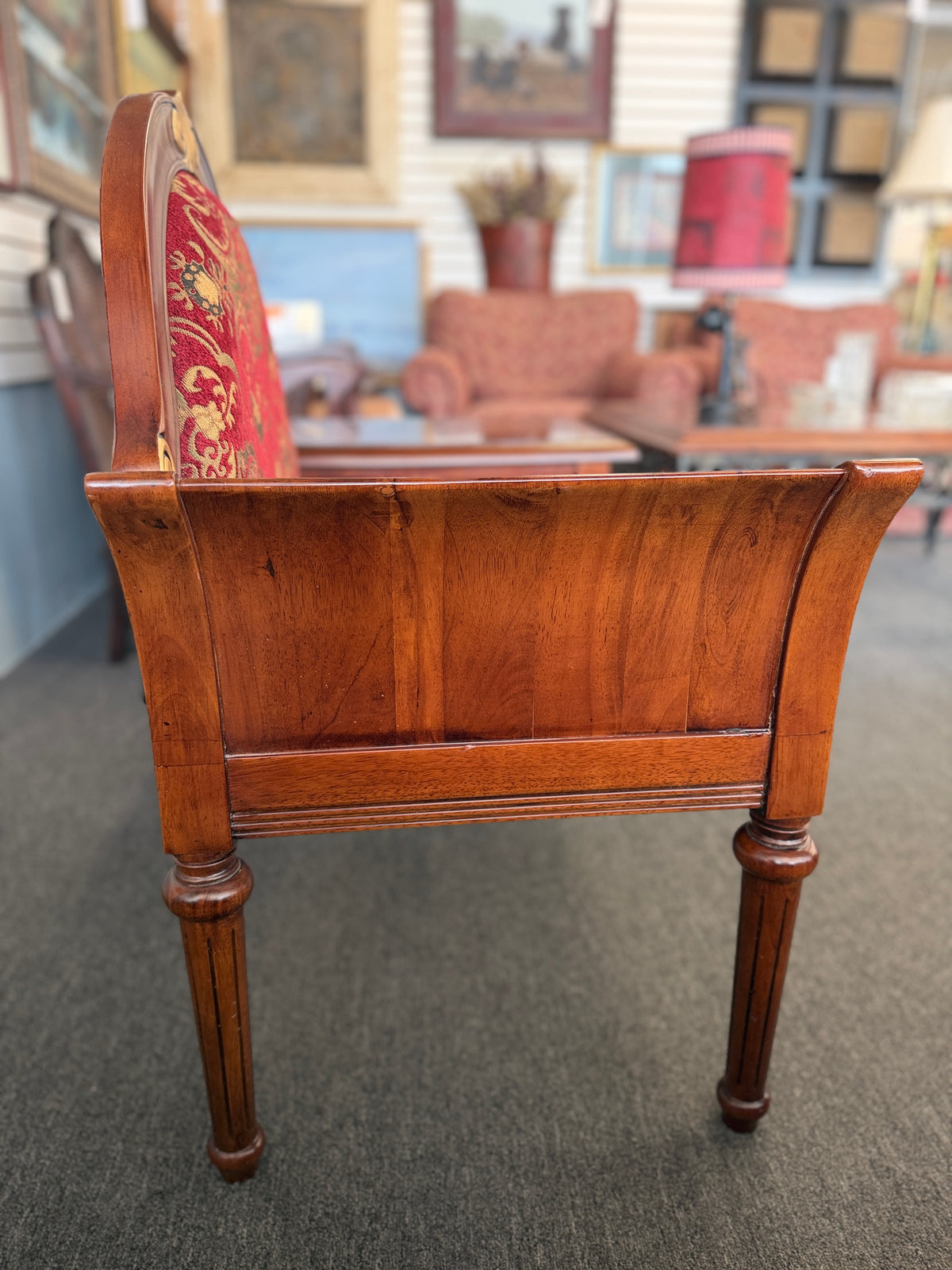 An antique-style wooden telephone chair featuring a single seat with red patterned upholstery, gold-accented scrollwork, an attached side tabletop, and a drawer in excellent condition.