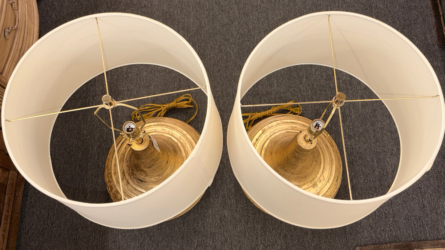 A pair of table lamps with wide teardrop-shaped bases featuring horizontal ribbing in an antiqued gold finish topped with white fabric drum shades.