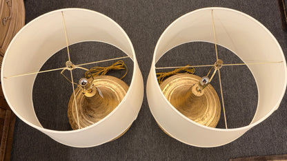A pair of table lamps with wide teardrop-shaped bases featuring horizontal ribbing in an antiqued gold finish topped with white fabric drum shades.