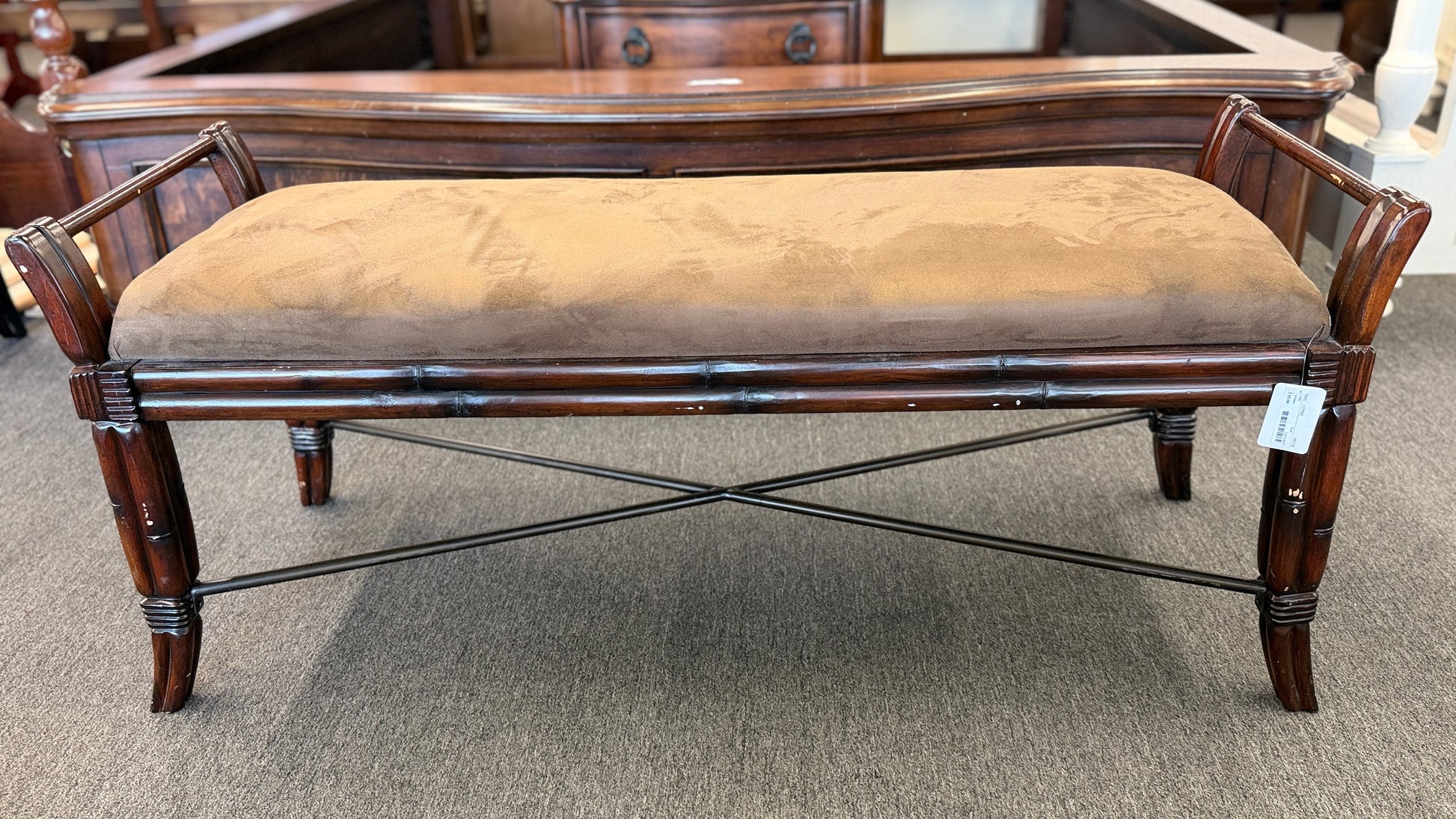 A wooden bench featuring bamboo-style framing, metal cross-stretchers, and a brown upholstered seat in good condition.