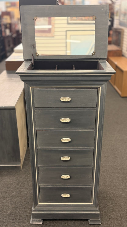 A tall slender Bassett jewelry armoire finished in distressed slate gray with white trim line detailing, six front drawers, and a flip-top lid with interior mirror in excellent condition.