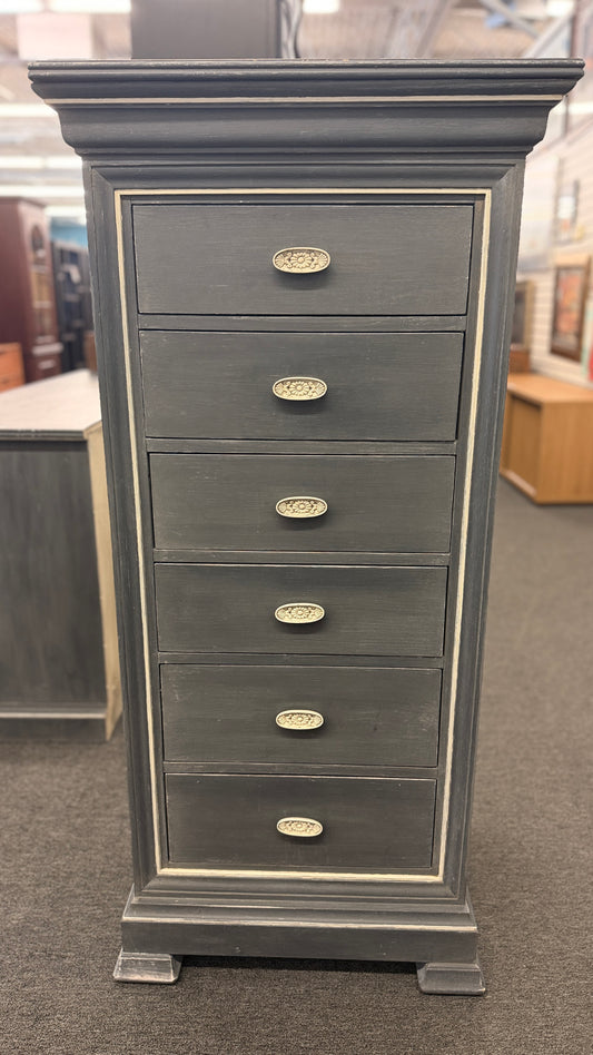 A tall slender Bassett jewelry armoire finished in distressed slate gray with white trim line detailing, six front drawers, and a flip-top lid with interior mirror in excellent condition.