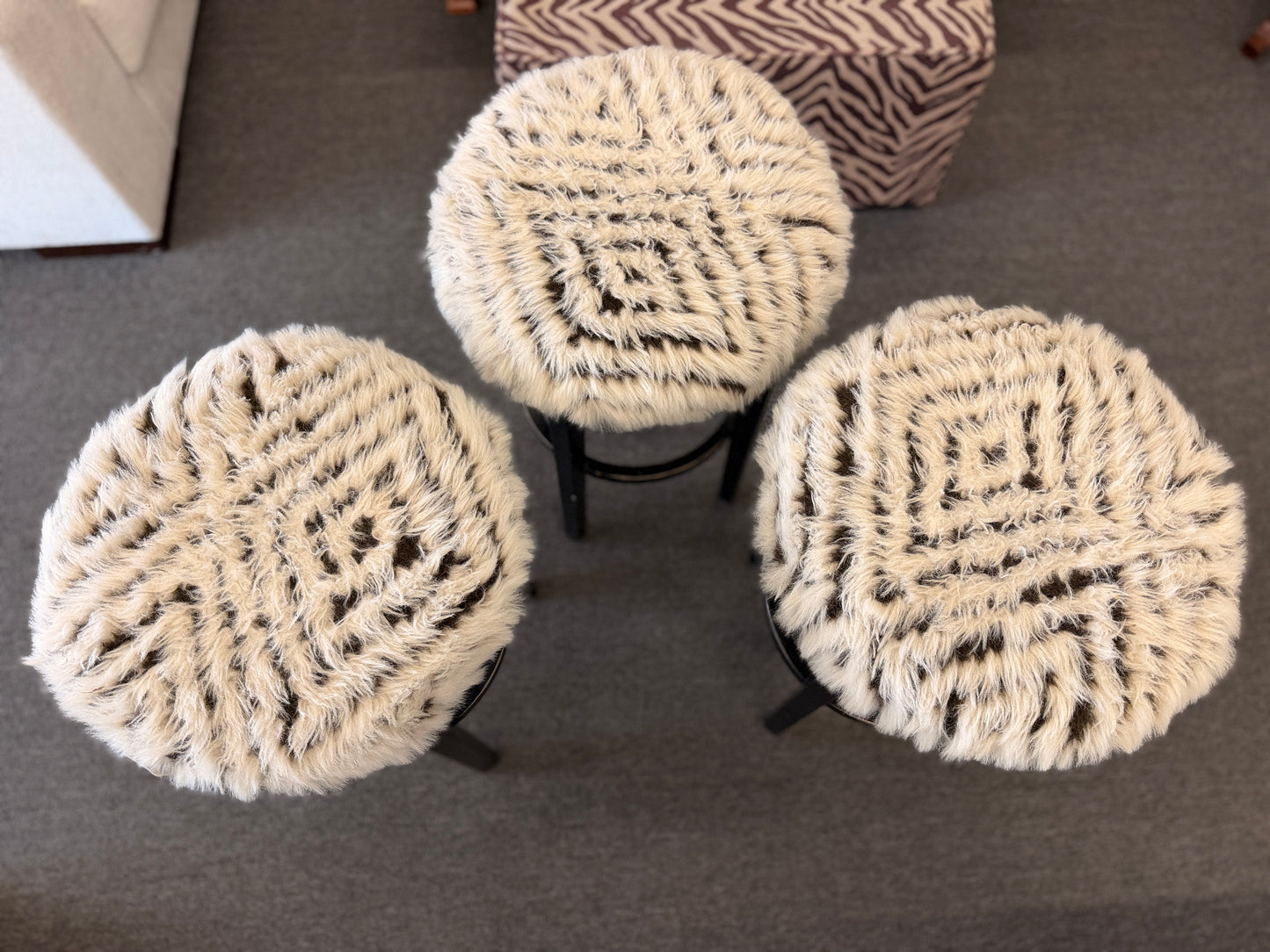 A set of three black wooden barstools featuring fluffy animal-print upholstered seats in good condition.