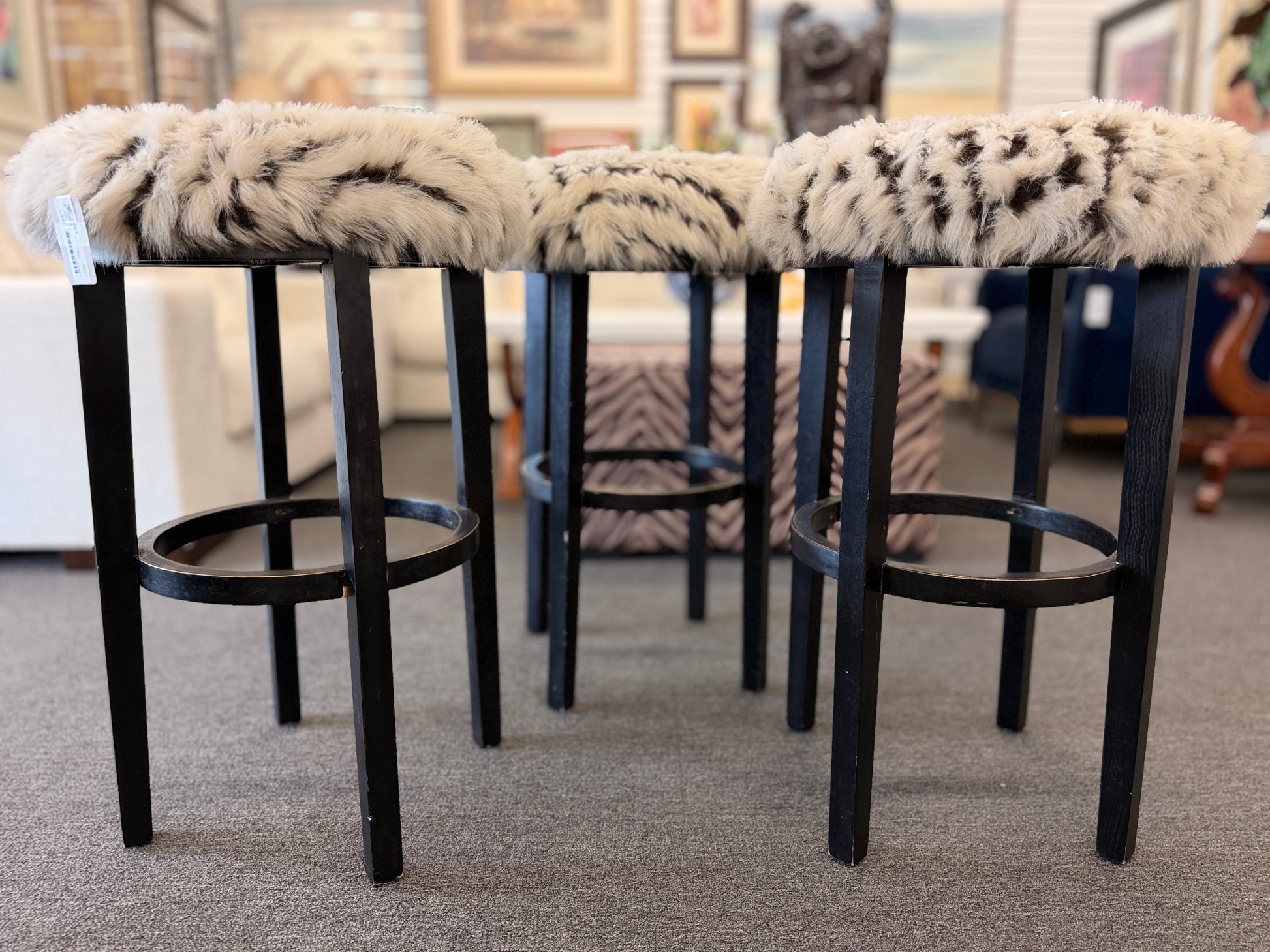 A set of three black wooden barstools featuring fluffy animal-print upholstered seats in good condition.