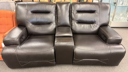Brown dual power reclining loveseat upholstered in leather with prominent stitched detailing, independent reclining seats, and a center storage console with padded armrests.