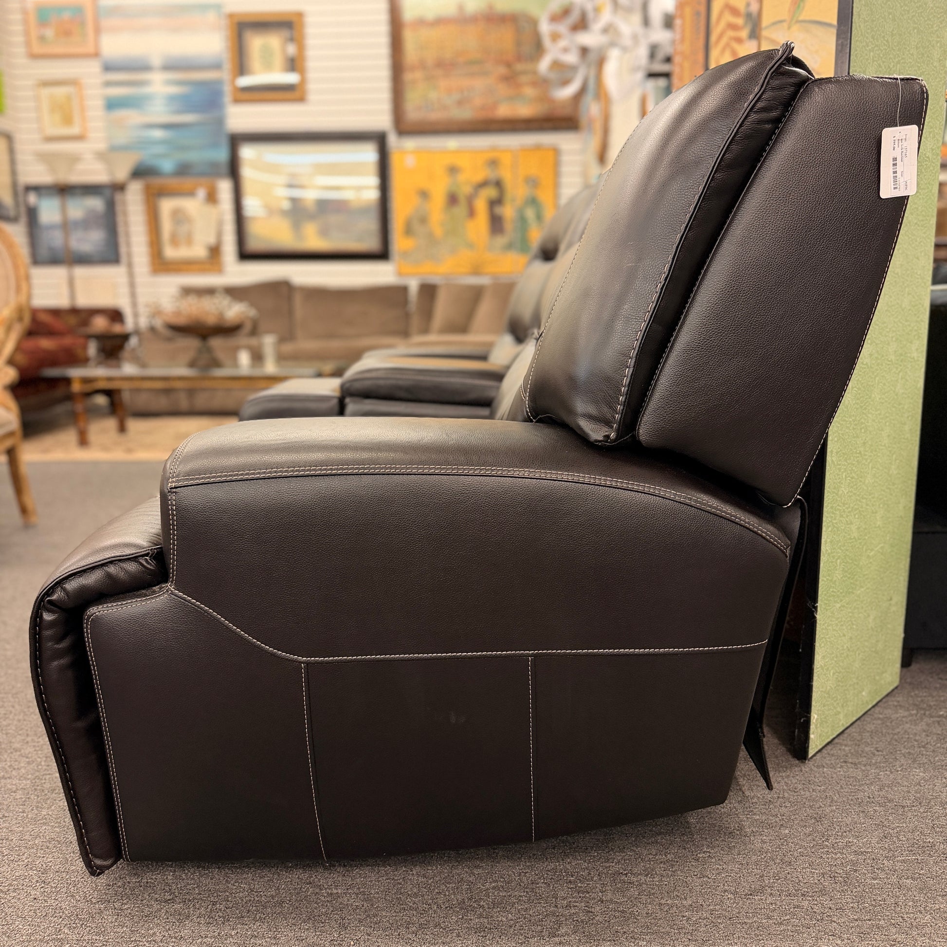Brown dual power reclining loveseat upholstered in leather with prominent stitched detailing, independent reclining seats, and a center storage console with padded armrests.