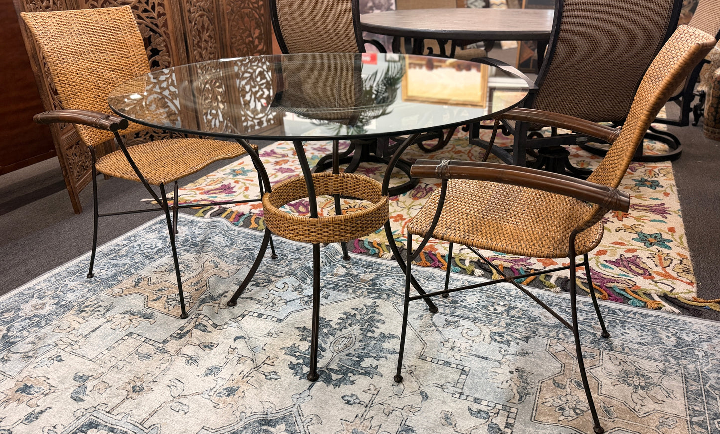 A 3-piece patio bistro set featuring a round glass-top table and two matching armchairs made of rattan and bamboo with curved metal legs.