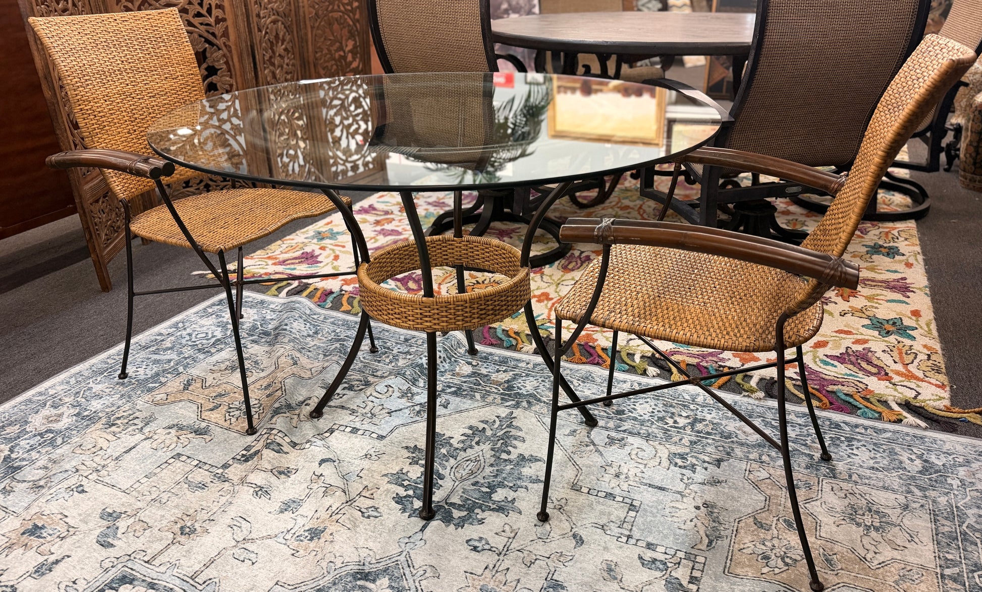 A 3-piece patio bistro set featuring a round glass-top table and two matching armchairs made of rattan and bamboo with curved metal legs.