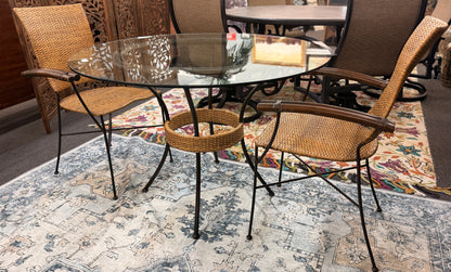 A 3-piece patio bistro set featuring a round glass-top table and two matching armchairs made of rattan and bamboo with curved metal legs.