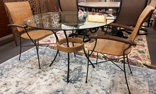 A 3-piece patio bistro set featuring a round glass-top table and two matching armchairs made of rattan and bamboo with curved metal legs.