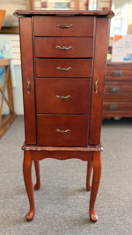A tall cherry-finished wooden jewelry cabinet on cabriole legs featuring pull-out drawers, swinging side doors, and a flip-top vanity mirror.