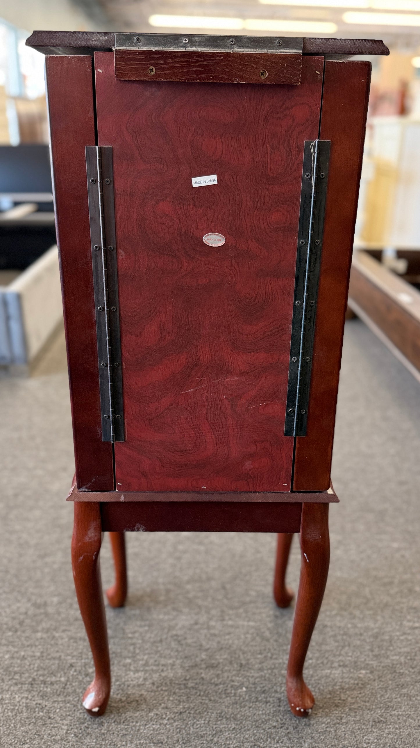 A tall cherry-finished wooden jewelry cabinet on cabriole legs featuring pull-out drawers, swinging side doors, and a flip-top vanity mirror.