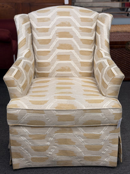 Fully upholstered wingback accent armchair with a tailored skirt featuring an off-white and tan or gold chevron-style geometric pattern in excellent condition.