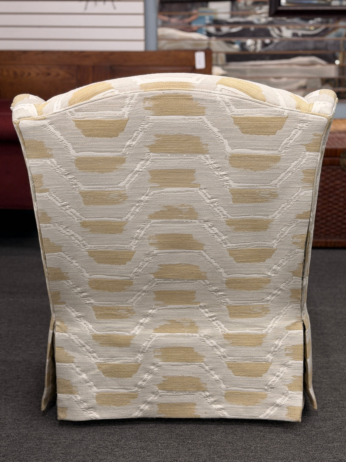 Fully upholstered wingback accent armchair with a tailored skirt featuring an off-white and tan or gold chevron-style geometric pattern in excellent condition.
