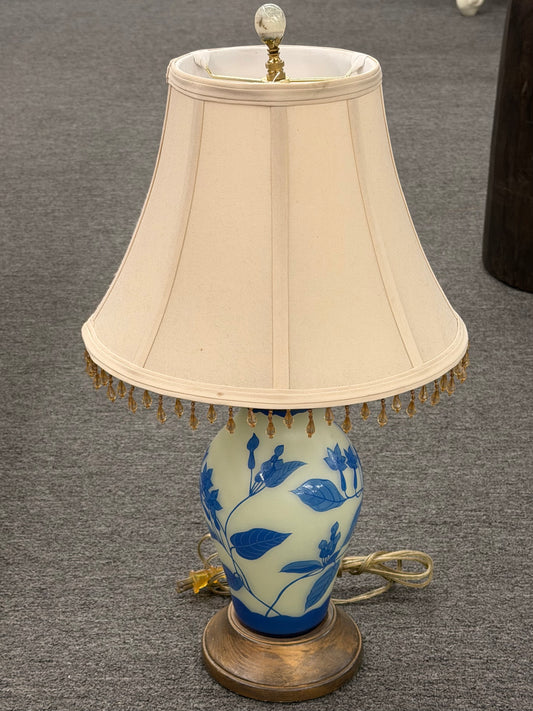 Traditional Chinoiserie blue and cream floral table lamp featuring a ceramic base with a blue floral design and a beige lampshade with beaded fringe decorative trim at 2nd Debut Houston consignment showroom
