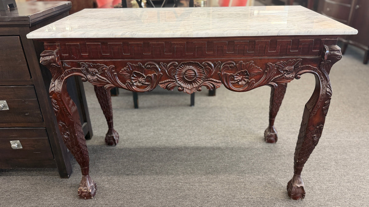 A Chippendale-style marble-top console table featuring an intricately carved mahogany apron, Greek key border, and cabriole legs with ball-and-claw feet in good condition.