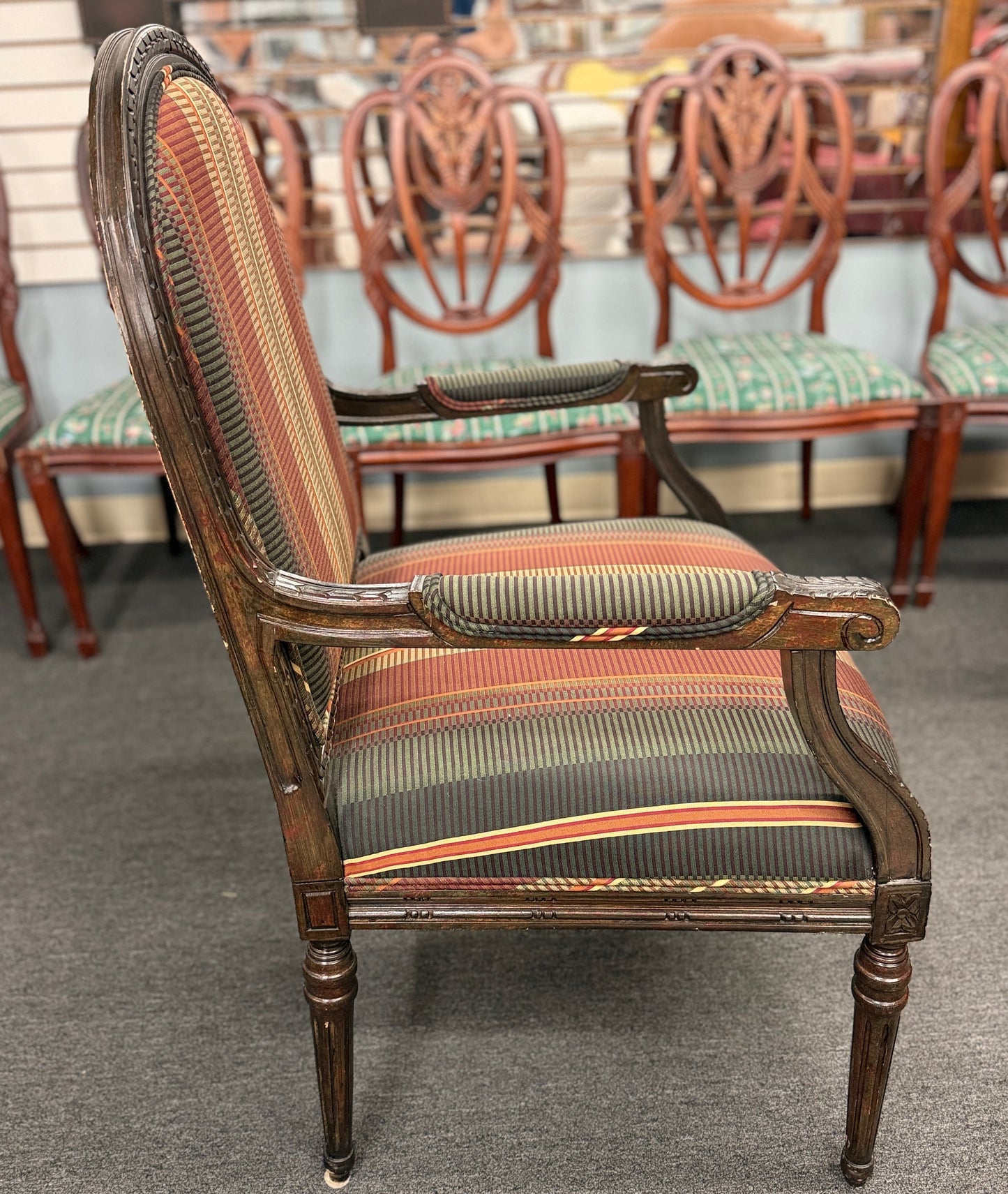 A classic French-style accent armchair with a dark wood frame, an oval medallion backrest, fluted straight legs, and traditional striped fabric upholstery.