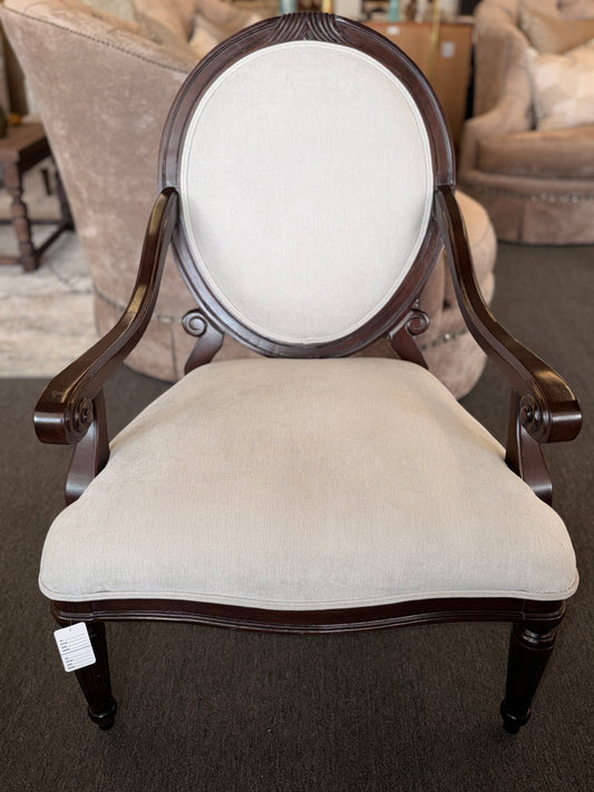 Classic oval-back accent chair with a dark wood frame, light beige upholstered seat and back, padded armrests, and fluted tapered wooden legs.