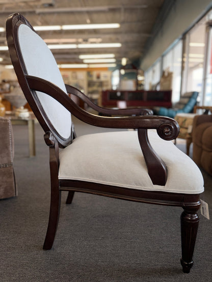 Classic oval-back accent chair with a dark wood frame, light beige upholstered seat and back, padded armrests, and fluted tapered wooden legs.