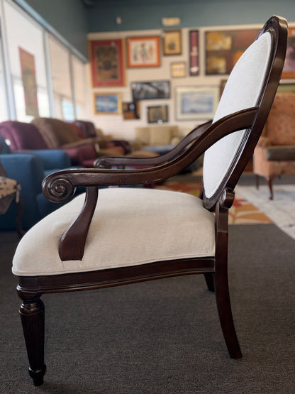 Classic oval-back accent chair with a dark wood frame, light beige upholstered seat and back, padded armrests, and fluted tapered wooden legs.