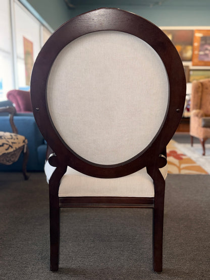 Classic oval-back accent chair with a dark wood frame, light beige upholstered seat and back, padded armrests, and fluted tapered wooden legs.