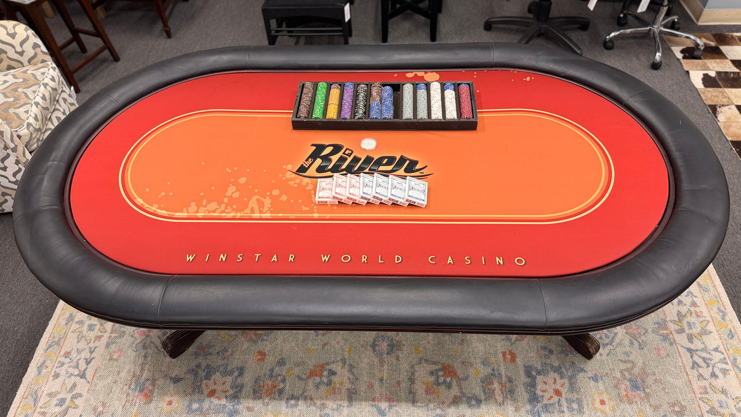 An oval-shaped Texas Hold'em poker table featuring a bright orange and red branded felt surface, black padded armrest ring, wood base, poker chips, and playing cards.