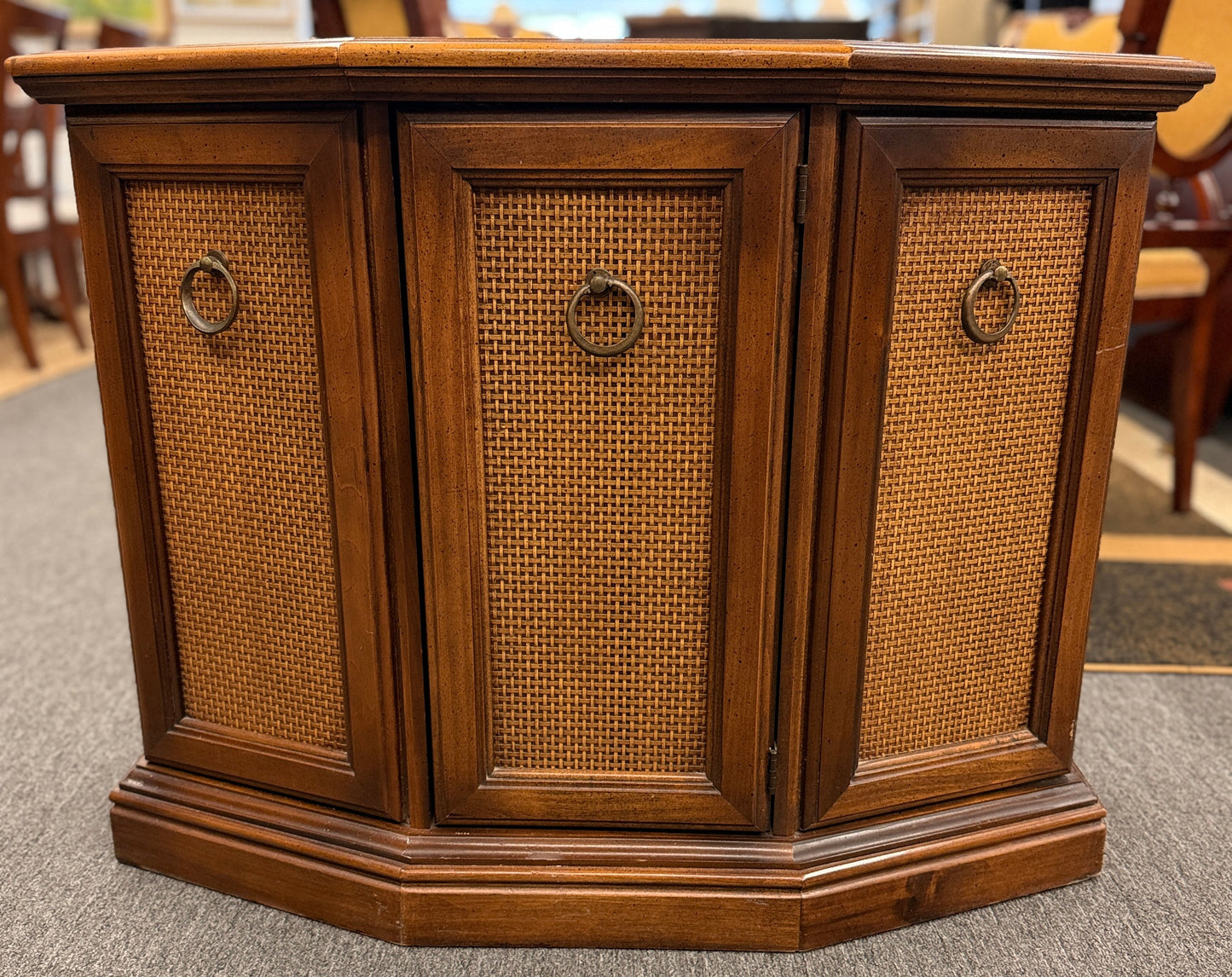 A classic wood accent cabinet featuring three front panels with decorative metal ring-pull hardware and a clean-lined wood frame.